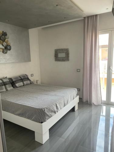 a white bedroom with a bed and a window at Deluxe Home appartamento in Sciacca