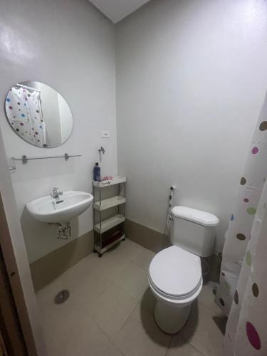 Un baño con inodoro, lavabo y espejo. en Inn the City, en Manila