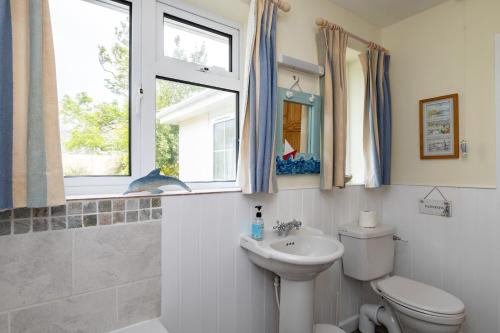 a bathroom with a sink and a toilet and a window at Pencreek in Padstow