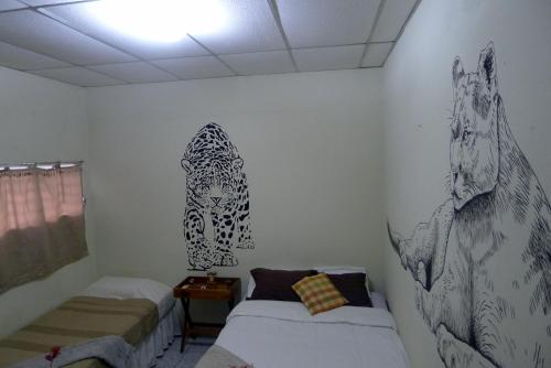 a bedroom with two beds and paintings on the wall at Matagalpa Tours Guest House in Matagalpa