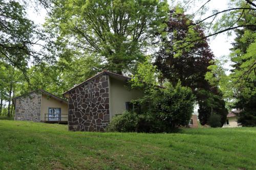Manot Vacances - Gites en bord de Vienne في Manot: مبنى حجري صغير في حقل عشبي