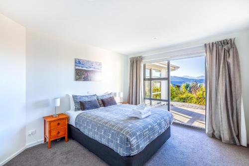 a bedroom with a bed and a large window at Tekapo Blue in Lake Tekapo