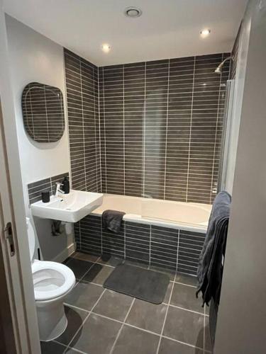 a bathroom with a toilet and a tub and a sink at Pettit Apartments - Central "Free Parking" in Liverpool