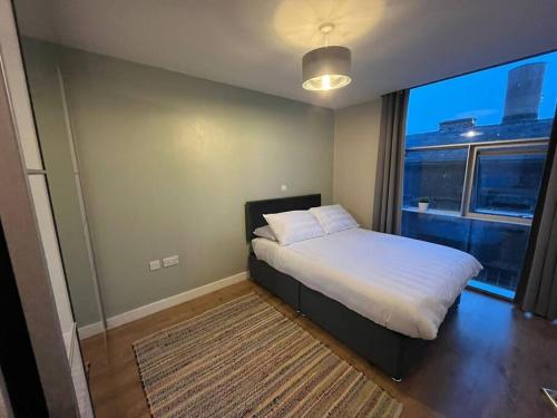 a bedroom with a bed and a large window at Pettit Apartments - Central "Free Parking" in Liverpool