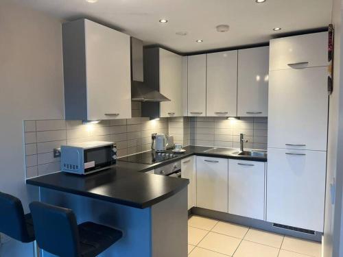 uma cozinha com armários brancos e um balcão com um micro-ondas em Pettit Apartments - Central "Free Parking" em Liverpool