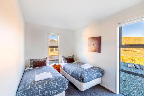 two beds in a room with a window at Tekapo Blue in Lake Tekapo