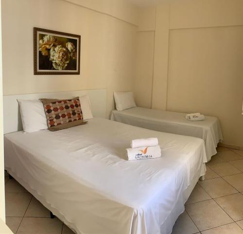 two beds in a room with white sheets at Apart Victoria in Vitória da Conquista