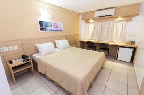 a small hotel room with a bed and a table at Arrey Gran Hotel in Teresina