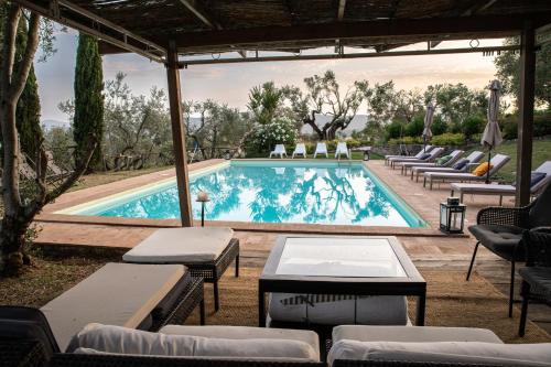 a swimming pool with lounge chairs and tables in front at Villa in Agello in Agello