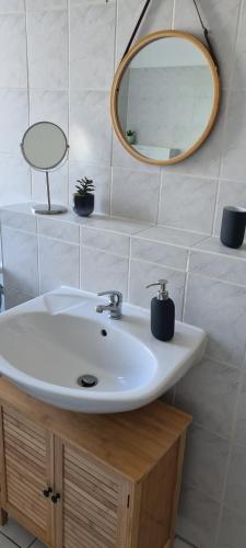 een badkamer met een witte wastafel en een spiegel bij Lichtdurchflutete moderne Stadtwohnung, Küche, Waschtrockner, SmartTV in Brandenburg an der Havel
