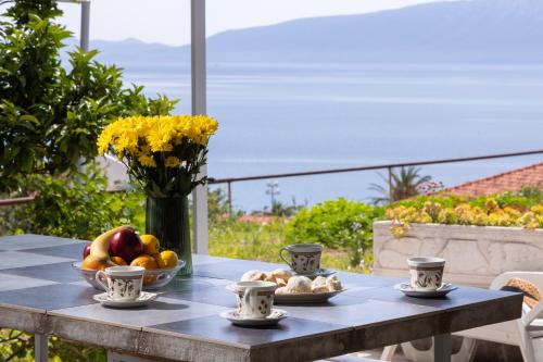 a table with a bowl of fruit and a vase of flowers at Apartments Nikolic in Gradac