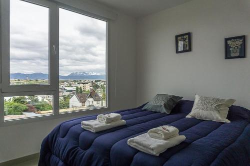 a bedroom with a large blue bed with towels on it at Gente del Sur - Goleta in Ushuaia