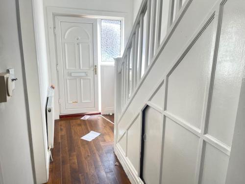 um corredor com uma porta branca e um piso de madeira em West Bishop Auckland Professional Let em Bishop Auckland
