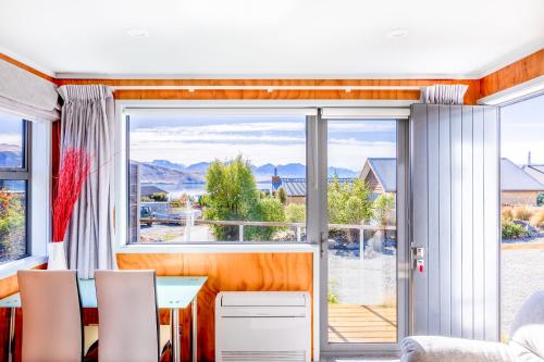 a living room with a table and chairs and a large window at Tekapo Blue Cottage in Lake Tekapo