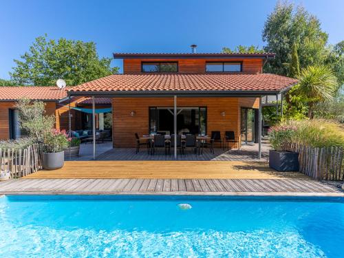 une maison avec une piscine en face d'une maison dans l'établissement Villa familiale 10 pers. à Biscarrosse avec piscine chauffée, près du lac et des pistes cyclables - FR-1-319-488, à Biscarrosse