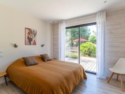 sypialnia z dużym łóżkiem i przesuwnymi szklanymi drzwiami w obiekcie Villa familiale 10 pers. à Biscarrosse avec piscine chauffée, près du lac et des pistes cyclables - FR-1-319-488 w mieście Biscarrosse