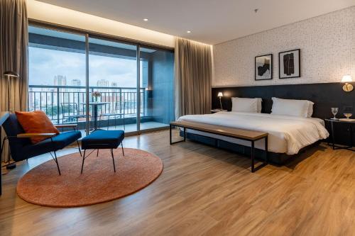 サンパウロにあるIntercity Tatuapéのベッドと大きな窓が備わるホテルルームです。
