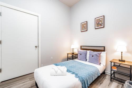 a white bedroom with a bed and two lamps at Park Ave Townhome w parking by CozySuites in Saint Louis