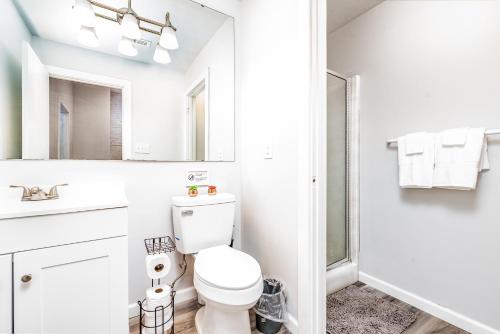 a white bathroom with a toilet and a sink at Park Ave Townhome w parking by CozySuites in Saint Louis