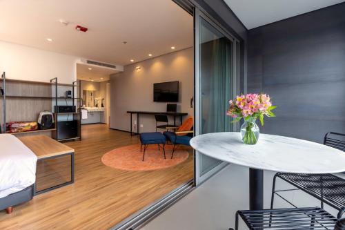 a room with a bed and a table with flowers on it at Intercity Tatuapé in Sao Paulo