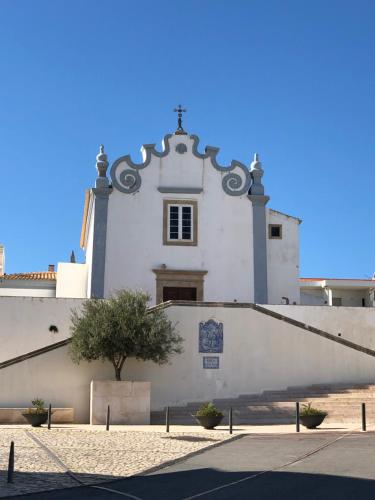 a white building with a cross on top of it at Apartamento flor de amendoeira in Albufeira