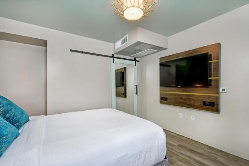 a white bedroom with a bed and a tv at Marea Sol Hotel in Santa Cruz