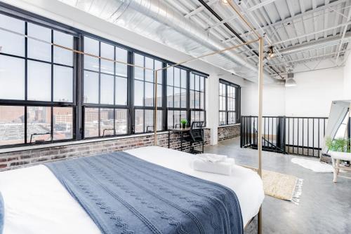 a bedroom with a bed in a room with large windows at CozySuites Stunning 2BR penthouse Skyline view in Saint Louis