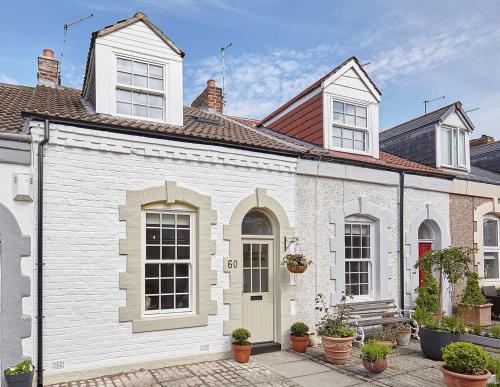 a white house with white windows and potted plants at Boutique Fisherman’s Cottage in Cullercoats