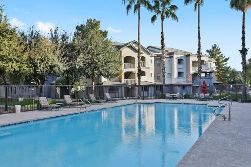 a large swimming pool with palm trees and a building at CozySuites Chandler with 2 pools, jacuzzi, arcade! in Chandler