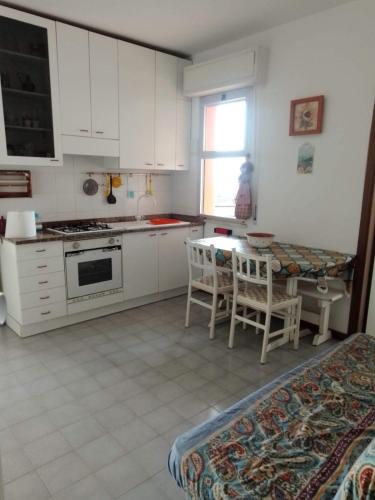 una cucina con armadi bianchi, tavolo e sedie di La casa di Alba ad Alba Adriatica