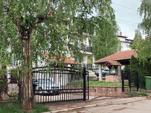 a black gate with a tree in front of a house at Grand Blue 2 Bedroom Apartment Sokobanja in Soko Banja