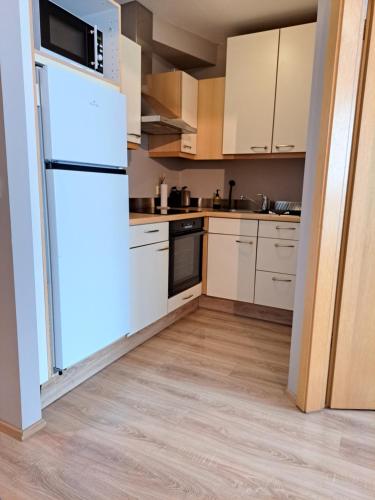 a kitchen with white cabinets and a refrigerator at H3 apartment - cozy downtown apartment in Akureyri