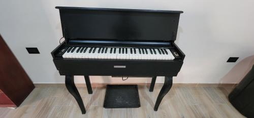 a black piano sitting on top of a wooden floor at Altea Hostal in Santa Ana