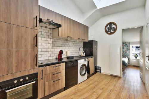 une cuisine avec des armoires en bois et une laveuse et une sécheuse dans l'établissement appartement Karibu à Lagnieu, à Lagnieu