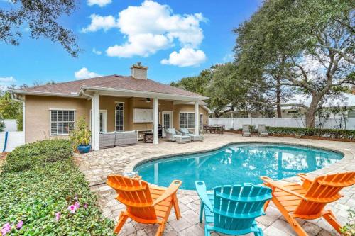 a home with a swimming pool with chairs and a house at Sandy's Seacrest in Inlet Beach