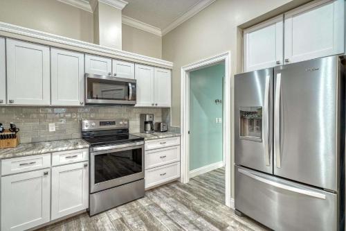 a kitchen with white cabinets and a stainless steel refrigerator at Sandy's Seacrest in Inlet Beach