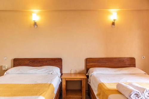two beds in a room with a table between them at Hotel El Mirador in Puerto Escondido