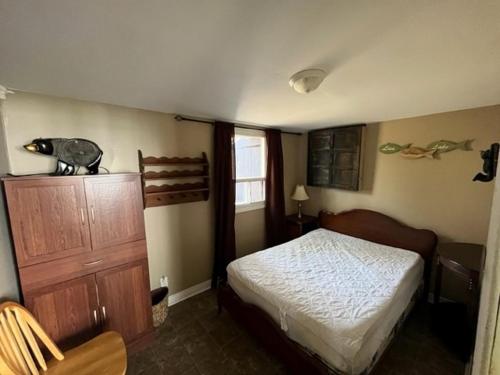 ein Schlafzimmer mit einem Bett und einer Holzkommode in der Unterkunft The “Bear” waterfront cabin in Muskoka in Utterson