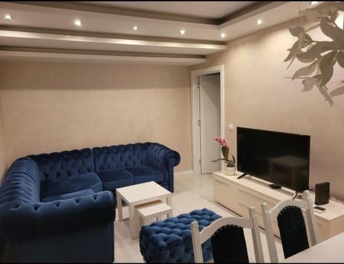 ein Wohnzimmer mit einem blauen Sofa und einem TV in der Unterkunft Apartman Cookie Kolačić blizu aerodroma Nikola Tesla in Dobanovci