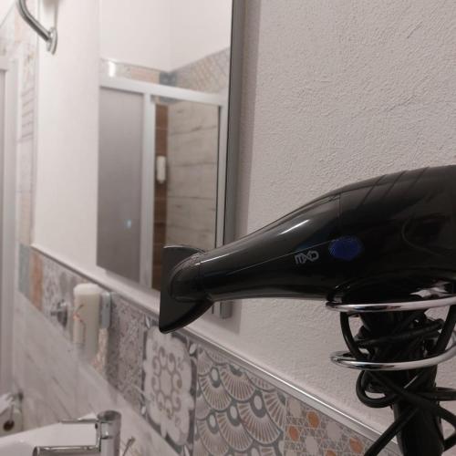 a black hairdryer hanging on a wall next to a mirror at Marea affittacamere in Porto Empedocle