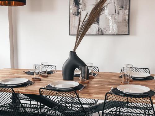 a wooden table with chairs and a vase on it at The Aspect, by Solace Stays in Cardiff