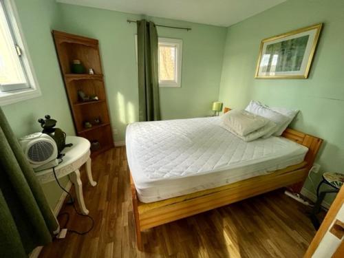 Schlafzimmer mit einem weißen Bett, einem Schreibtisch und einem Fenster in der Unterkunft The “Lily” waterfront Muskoka cottage in Utterson