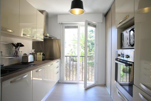 een keuken met witte kasten en een groot raam bij Centru Appart lumineux vue mer 5 min à pied de la plage et du centre in Calvi