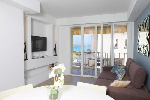 een woonkamer met een bank en een televisie bij Centru Appart lumineux vue mer 5 min à pied de la plage et du centre in Calvi