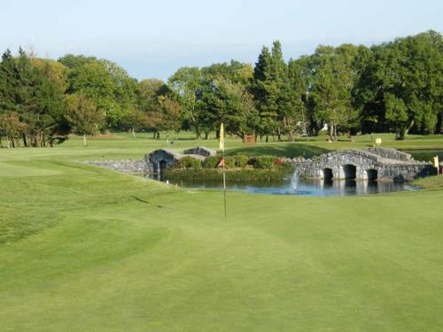 a golf course with a stone bridge and a pond at Rocklands Guesthouse in Castlebar