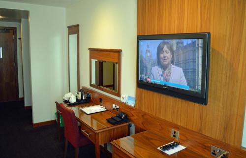 a room with a television on a wall with a table at Best Western Kings Manor in Edinburgh