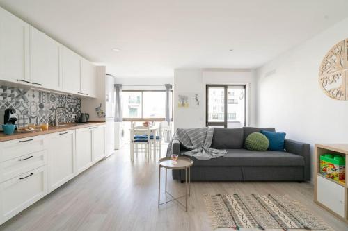 a living room with a couch and a kitchen at Casa Oliveira - Sunny 2-Bed Retreat Steps from the Beach in Armação de Pêra