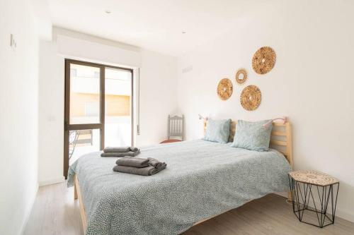 a white bedroom with a large bed and a window at Casa Oliveira - Sunny 2-Bed Retreat Steps from the Beach in Armação de Pêra
