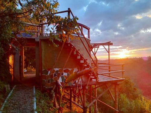 a cow standing next to a building with the sunset in the background at HakunaMatata glamping Pumba in Salento