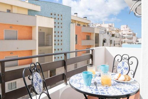 a balcony with a table and chairs with drinks on it at Casa Oliveira - Sunny 2-Bed Retreat Steps from the Beach in Armação de Pêra